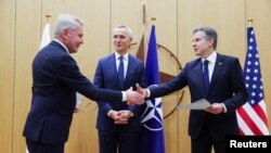 Finnish Foreign Minister Pekka Haavisto (left) shakes hands with U.S. Secretary of State Antony Blinken as NATO Secretary-General Jens Stoltenberg looks on during an accession ceremony at a NATO foreign ministers' meeting in Brussels on April 4.