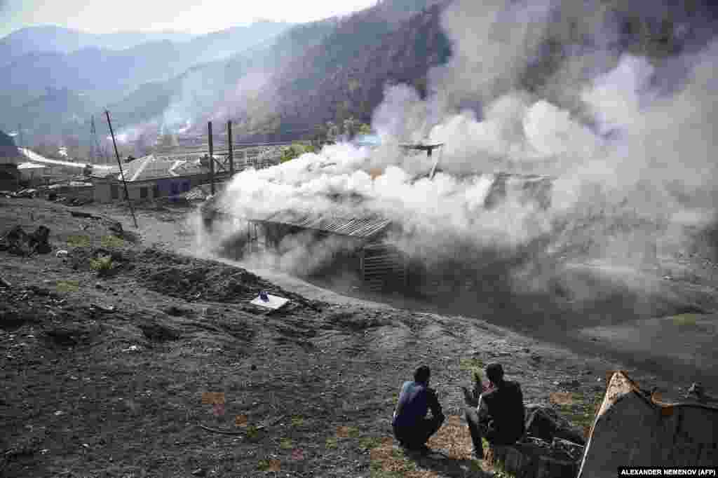Residents watch houses smolder in Charektar village, known in Azeri as Caraktar, in the district of Karvachar (Kalbacar in Azeri). The mountainous district in Azerbaijan to the west of Nagorno-Karabakh is being vacated by Armenians and returned to Baku’s control under a Russian-brokered truce.