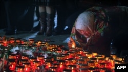 A woman lights a candle at the monument to victims of the Holodomor, Ukraine's great famine in 1932-33, in Kyiv on November 24