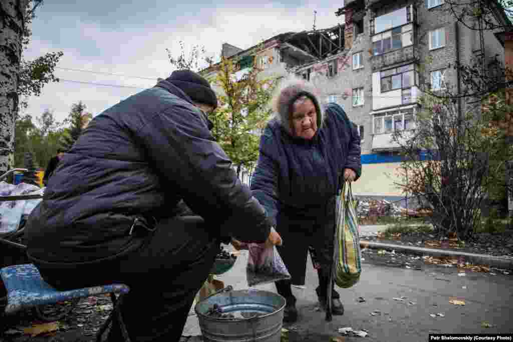 Nikolai sells grapes, grown in his own garden, to an elderly woman in front of a destroyed building in Gorlovka. According to the new separatist mayor, 80 percent of the city's population has returned to their homes. Job opportunities are still very limited