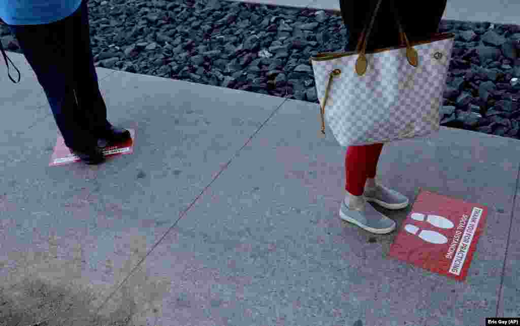Signs that assist with social distancing are used by shoppers who wait in line at a grocery store in Austin, Texas, on March 25.