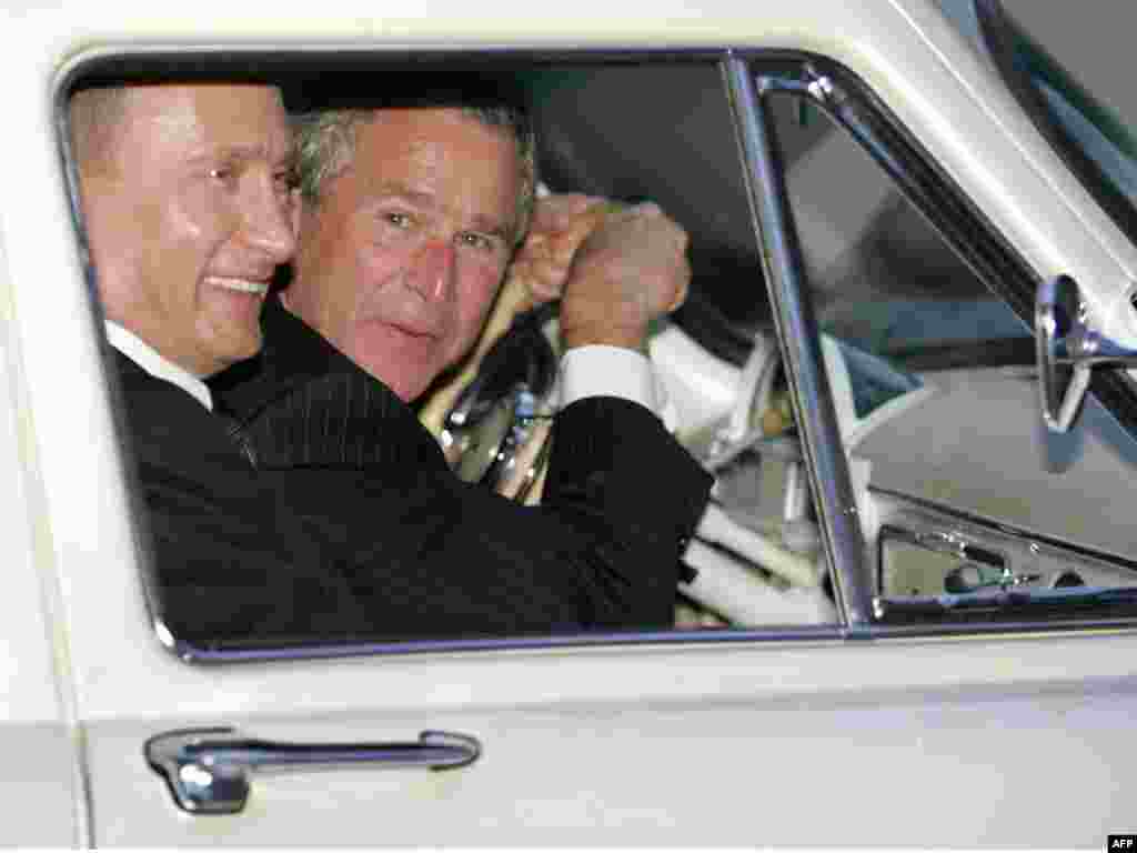 U.S. President George W. Bush leans over the steering wheel while driving Russian President Vladimir Putin's 1956 Volga outside Moscow in May 2005.