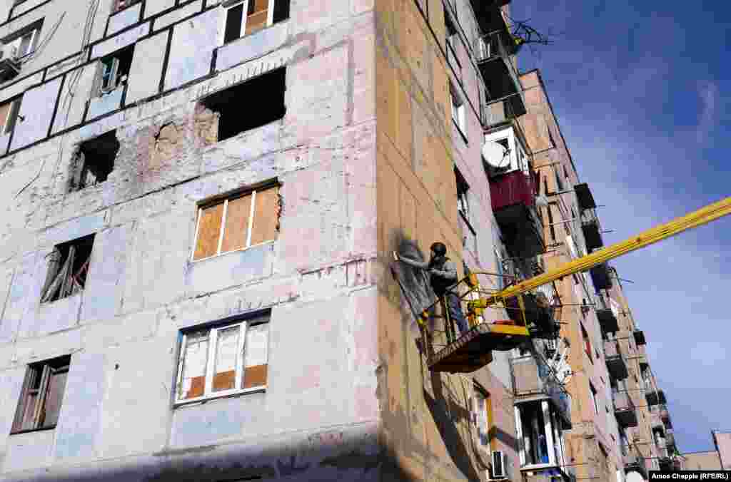 Damage from an artillery or tank round above where Van Helten works. The building has stood empty since 2014, after a Grad (Hail) rocket landed in one of the apartments, killing two civilians inside. 