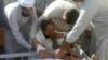 په صوابۍ کې د يوه وژل شوي ځوان د جنازې کټ ته د هغه خپلوان او ملګري غونډ شوي - عکس له ارشېفه 